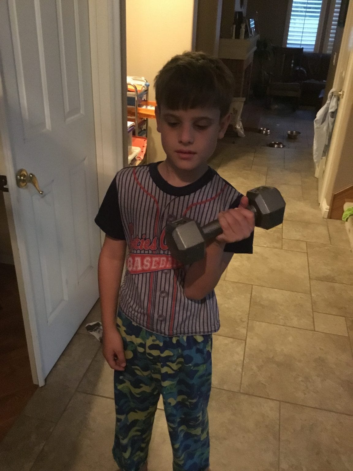 Strength Training- a young boy lifts a dumbbell