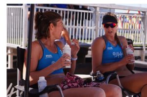 Volleyball Nutrition: 2 sand volleyball players shown drinking fluids during a match time-out